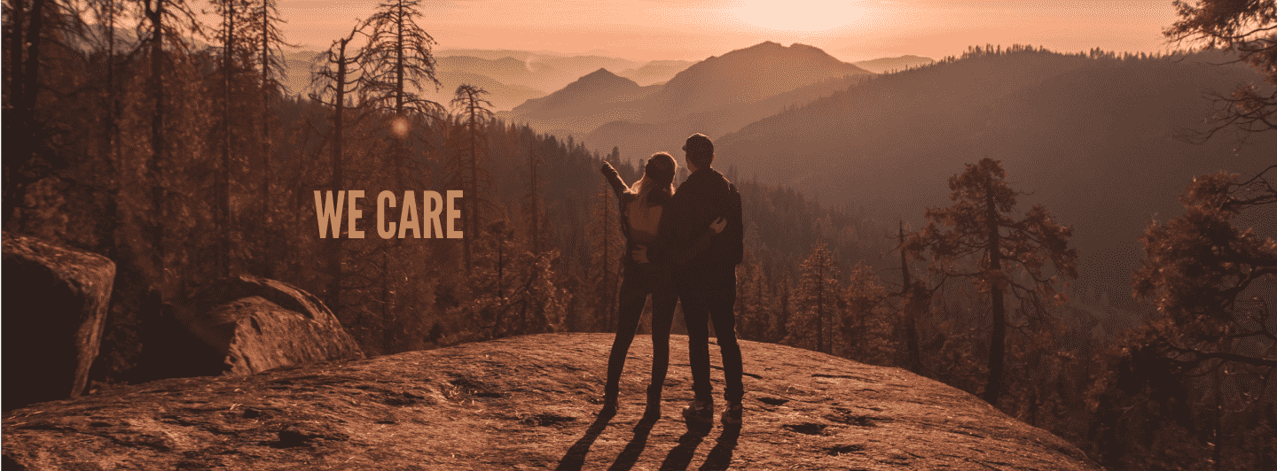 happy group standing on a mountain with a misty sunset