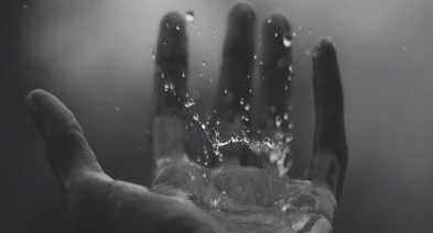 A hand with water drops splashing in black and white